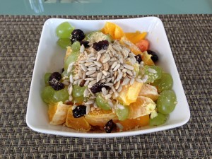 Basisches Müsli mit Mango, Trauben, Orangen, Cranberries und gerösteten Sonnenblumenkernen