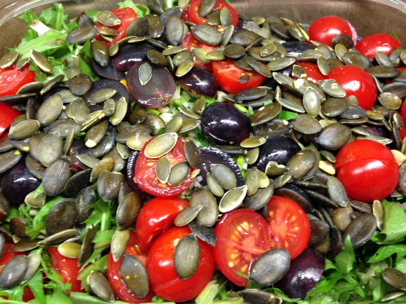 Löwenzahn Salat mit Avocado, Radicchio, Trauben, Tomaten und Kürbiskernen