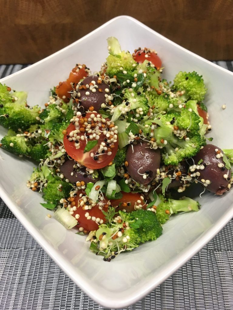 Brokkoli Salat mit getrockneten Tomaten, schwarzen Oliven, Kichererbsen und Quinoa Sprossen