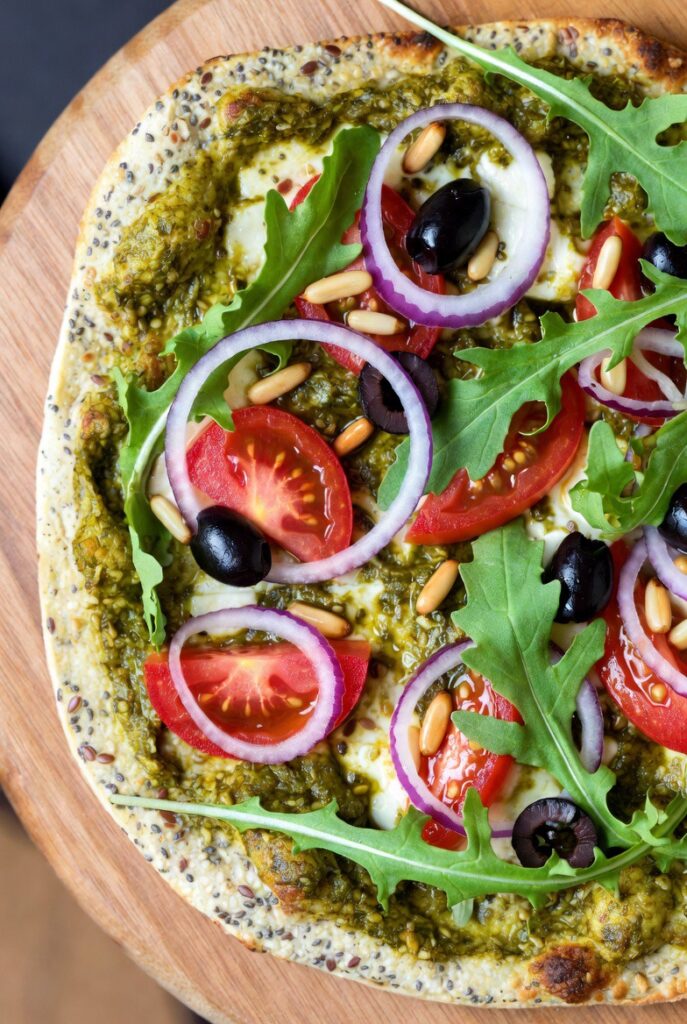 Pizza mit Pesto, Tomaten, Pinienkernen und Rucola