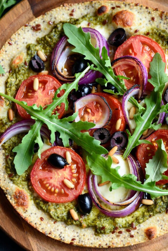 Pizza mit Pesto, Tomaten, Pinienkernen und Rucola