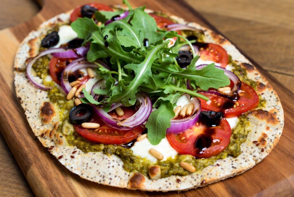 Pizza mit Pesto, Tomaten, Pinienkernen und Rucola