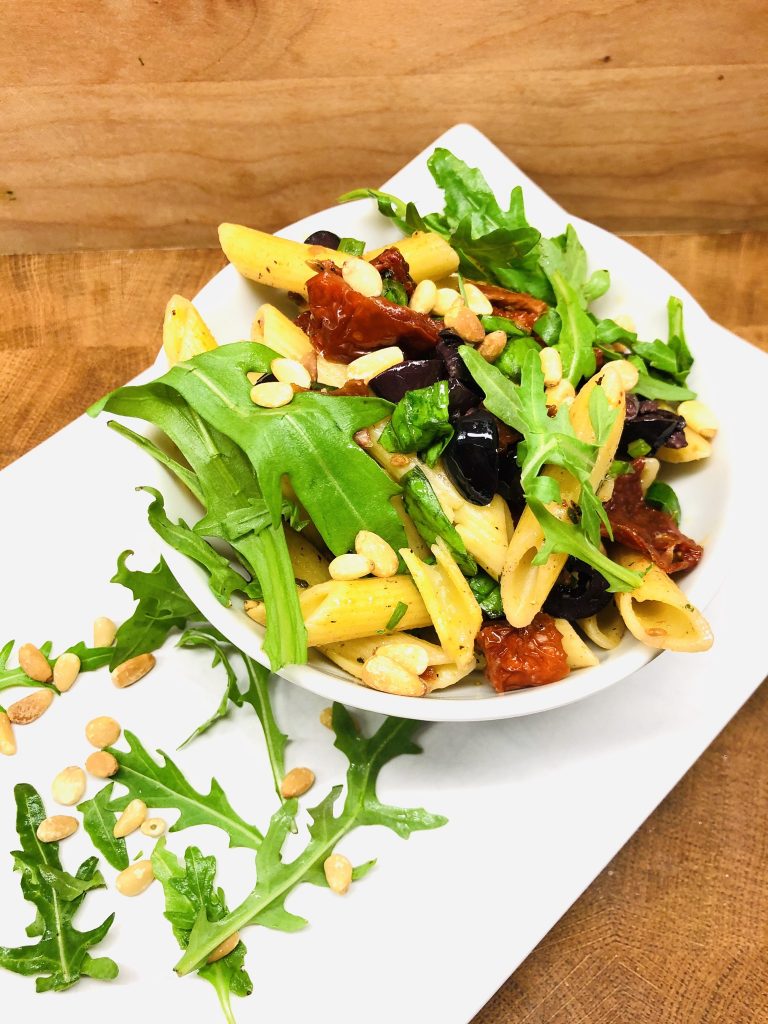 Nudelsalat mit Tomaten, Oliven, Rucola und Pinienkernen